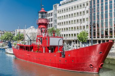 Red boat anchored at the quay of the port of Wijnhaven in the center of Rotterdam with buildings in the background, sunny day with a blue sky in the Netherlands Holland