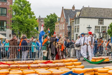 Alkmaar, North Holland / Netherlands. June 11th. 2016. Dutch cheese market with a large crowd, cheeses in the square, cheese bearers with straw hats and people in vintage clothing