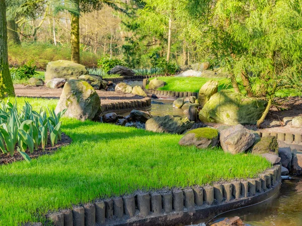 Lisse, South Holland / Netherlands, March, 20th, 2014. Garden with a small artificial zig zag canal surrounded by trees and green vegetation in the keukenhof park