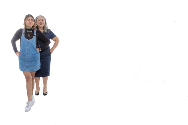 ラテン系女性の2世代 10代の娘 白いスタジオの背景と彼女の中年の母親の後ろに 広い笑顔 光の化粧 カメラ カジュアルなスタイル デニムの服を見て テキストのスペース — ストック写真