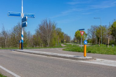 Kırsal yol kavşağı, Stevensweert, Maasbracht ve Eindhoven yönünü gösteren işaretler, trafik işaretleri: Güney Limburg, Hollanda 'da sürüş yönünü ve yol verme yönünü gösteren ok