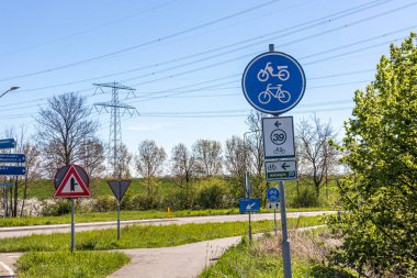 Farklı yol işareti: bisiklet ve moped yolu, 39 ve Maasrute yolları, sonraki kavşak, bisiklet yolu, kır yolu, arka planda ağaçlar, Stevensweert, Güney Limburg, Hollanda 'da güneşli bir gün