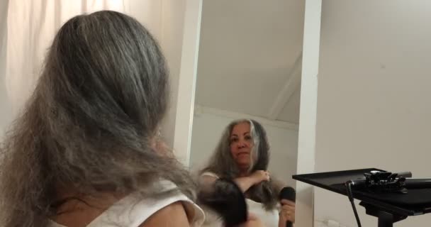 Зрелая Женщина Расчесывает Свои Серо Черные Волнистые Волосы Глядя Себя — стоковое видео