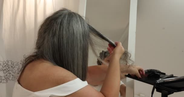 Dojrzała Kobieta Czesająca Przekazująca Przesuwająca Prostownicę Szaroczarne Włosy Wyprostowująca Proces — Wideo stockowe