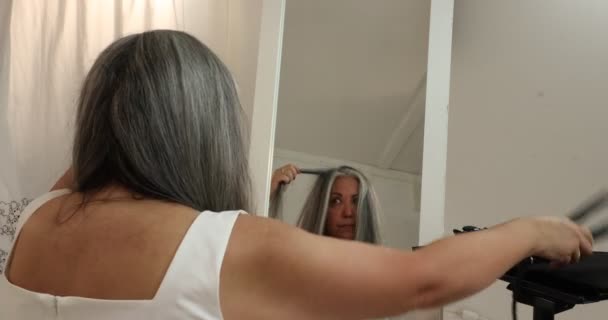Dojrzała Kobieta Przesuwa Prostownicę Nad Kosmykiem Włosów Koncentrując Się Procesie — Wideo stockowe