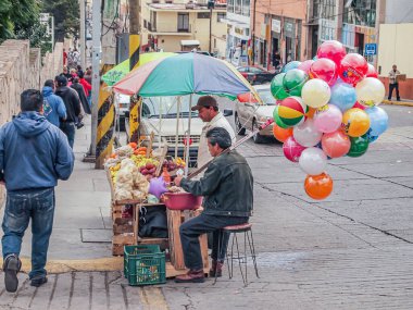 Zacatecas, Mexico. December 12, 2009. Mexican urban scene, street vendor selling fruits, other colorful balloons on a corner, people walking on the sidewalk, parked cars, normal day in the city