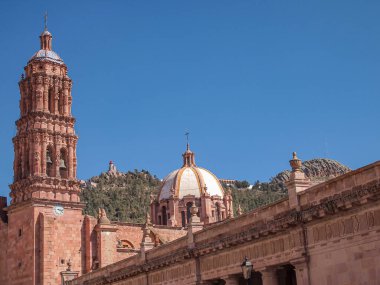 Zacatecas Katedral Bazilikası 'nın kısmi görüşü. Cerro de la Bufa arka planda bir çan kulesi ile katedralin kubbesi arasında güneşli bir günde Zacateca Mexico 'da.