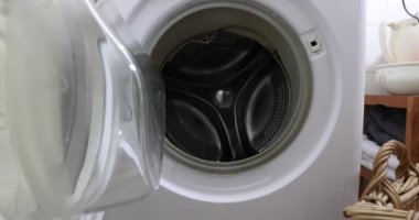 Kirli çamaşırları yıkamak için çamaşır makinesine koyan kadın elleri. Ev işleri konsepti