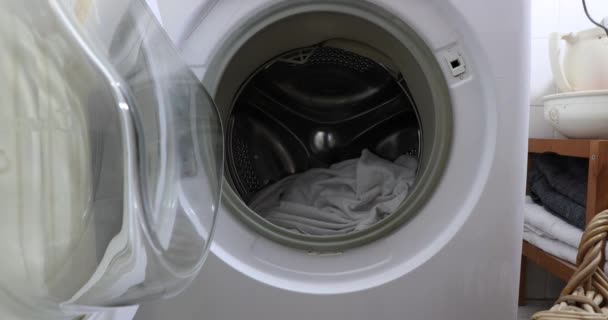 洗浄する洗剤と一緒に洗濯機に汚れた服を置く女性の手 家庭における家事の概念 — ストック動画