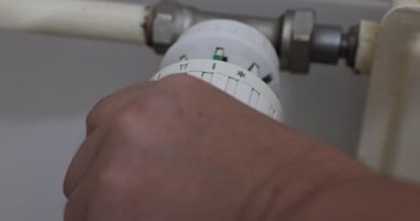 Kadın elleri sıcaklık valfini döndürerek radyatörün termostatını maksimum kapasitesine ayarlar ve evde sıcak bir sıcaklık sağlar. Dünya doğalgaz krizi kavramı