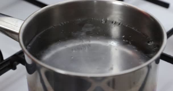 在煤气炉上对清洁透明的开水 气泡和飞溅 黑色烤炉 白色炉灶 金属锅进行近距离检查 家庭食品概念 — 图库视频影像
