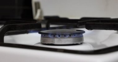Mutfaktaki yanan gaz sobasının üst açısı, siyah tavayı, arka planda yansıması olan beyaz yüzeyi, küçük mavi alevi, benzin fiyatlarındaki artışı gösteriyor. Avrupa Birliği 'nde enerji krizi kavramı