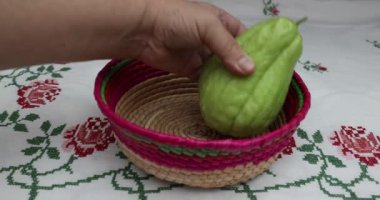 Dişi eller, Meksika hasır sepetine iki chayote yerleştiriyor çapraz dikişli çiçekler, labu siam, jipang organik sebzeler. Biyolojik, biyolojik ve evde yetiştirme kavramı