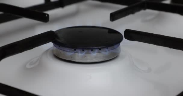 厨房里的燃气灶顶部的角度视图 放置黑色的平底锅 白色的表面在模糊的背景下反射 蓝色的小火焰 油价上涨 欧洲联盟的能源危机概念 — 图库视频影像