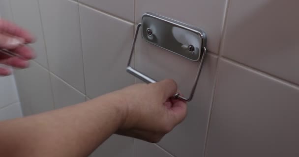 成年女性手将白色纸卷放在浴室墙壁上的卫生纸架上 空的铬金属卫生纸架 米黄色瓷砖 日常生活概念 — 图库视频影像