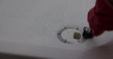 Kirli duş giderlerini ovalayan ve açan kırmızı eldivenli eller, derin temizlik ve açı için, siyah fırça, deterjan, beyaz metal yüzey, bakım görevi. Temizlik ve ev işi kavramı