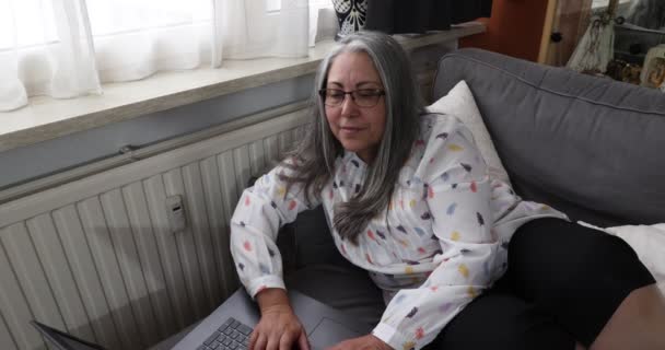 Ανώτερη Ενήλικη Γυναίκα Ξαπλωμένη Στον Καναπέ Χρησιμοποιώντας Laptop Της Επικεντρωμένη — Αρχείο Βίντεο