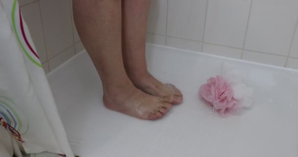床にシャワー ピンクと白のスポンジで大人の女性の女性の足と足の上に落ちる水 女性はさわやかなシャワーを浴びて 家庭での衛生とリラクゼーションの概念 — ストック動画