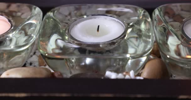 用玻璃杯烛台中的火柴点燃茶点的特写 在另外两支蜡烛 小石块之间 给人一种宁静祥和的感觉 黄色的火焰 信仰和希望的概念 — 图库视频影像