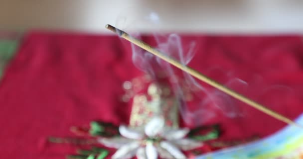 瞑想とリラクゼーションのために配置された軽い煙で焼香スティックのクローズアップ ぼやけた背景にクリスマスの装飾とテーブルクロス ホームウェルネスコンセプト — ストック動画
