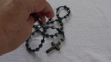 Yetişkin bir kadının elleri hematit taşı boncuklardan bir tespih alıyor, hasta ve dünya barışı için dua ediyor, parlak gri bir renk. İnanç ve umut kavramı
