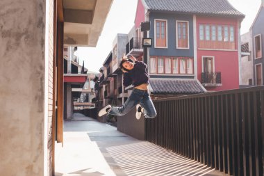 Müzik dinleyen ve kulaklıkla sokaklarda eğlenen mutlu Asyalı genç kadın..