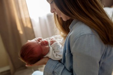 Uzun saçlı, genç ve güzel bir anne kucağında yeni doğmuş bir oğlu var.