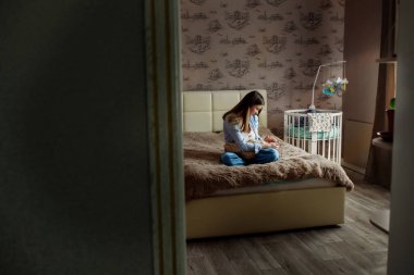 Uzun saçlı, genç ve güzel bir anne kucağında yeni doğmuş bir oğlu var.