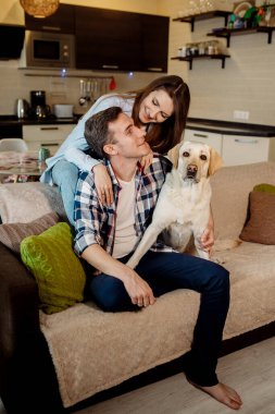 Genç çift ve tüylü bebek labrador av köpekleri mutfakta.