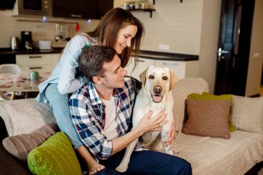 Genç çift ve tüylü bebek labrador av köpekleri mutfakta.