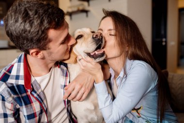 Genç çift ve tüylü bebek labrador av köpekleri mutfakta.
