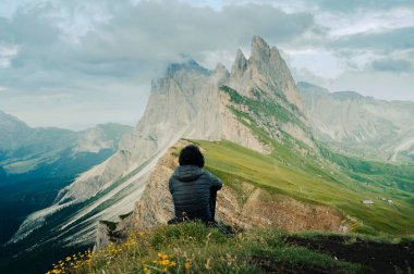 Arkadan Seceda dağlarının yamacında oturan adam.