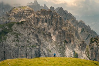 Mavi ceketli bir adam İtalyan Alplerinde bir Dolomite dağında duruyor.