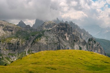 Mavi ceketli bir adam İtalyan Alplerinde bir Dolomite dağında duruyor.