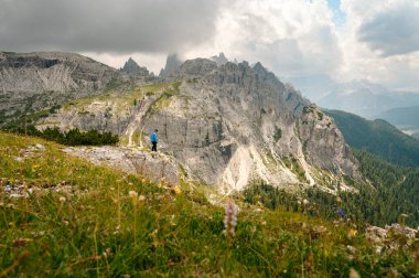 Mavi ceketli bir adam İtalyan Alplerinde bir Dolomite dağında duruyor.