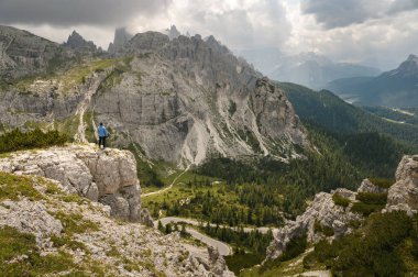 Mavi ceketli bir adam İtalyan Alplerinde bir Dolomite dağında duruyor.