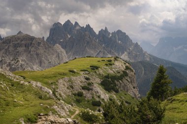 İtalya, Tre Cime 'deki Dolomite Dağları, güneşli yaz gününde mavi gökyüzü boyunca yeşil çimen önü