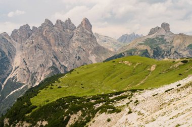 İtalya, Tre Cime 'deki Dolomite Dağları, güneşli yaz gününde mavi gökyüzü boyunca yeşil çimen önü