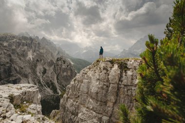 Mavi ceketli bir adam İtalyan Alplerinde bir Dolomite dağında duruyor.