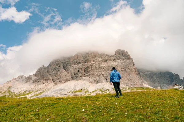 イタリアのドロマイト山の上に立つ青いジャケットの男山を背景に — ストック写真