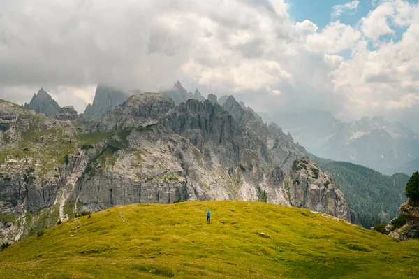 イタリアのドロマイト山の上に立つ青いジャケットの男山を背景に — ストック写真