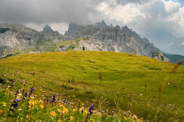 イタリアのドロマイト山の上に立つ青いジャケットの男山を背景に — ストック写真