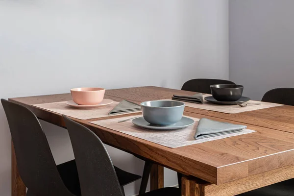 Stylish dining room interior with a wooden table set for three people with bowls and cutlery