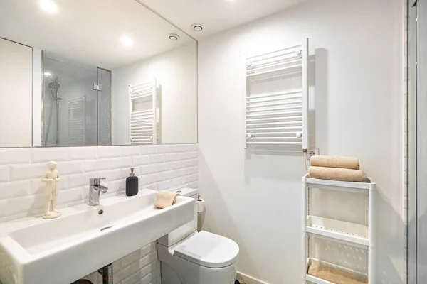 Belső tér fehér fürdőszoba felújított lakásban. Zuhanyzóna fűtőberendezéssel, mosogatóval és tükörrel Stock Fotó