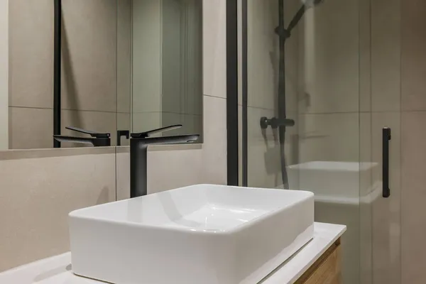 Közelkép a fehér mosogató fekete csap és tükör. Modern stílusú fürdőszoba a felújított lakásban. — Stock Fotó