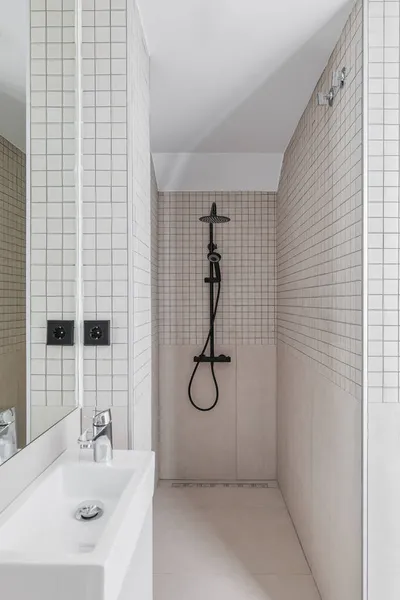 Cuarto de baño estrecho con zona de ducha y lavabo pequeño. Interior de baño moderno con azulejos beige. —  Fotos de Stock