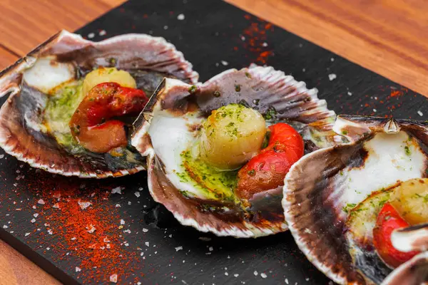 Cooked scallops on blackstone slate plate with species. Variety of Mediterranean seafood.