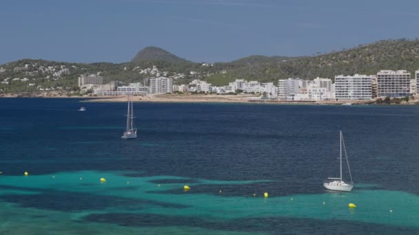 Yates anclados en el mar azul cerca de la orilla con muchos hoteles blancos en las Islas Baleares, Ibiza, España — Vídeos de Stock