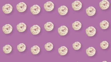 Pembe arka planda gölgeli izole edilmiş renkli çörek deseni. Donutla kusursuz desen. Çörekler. Üst Manzara. Gerçekçi animasyon. 4K video hareketi