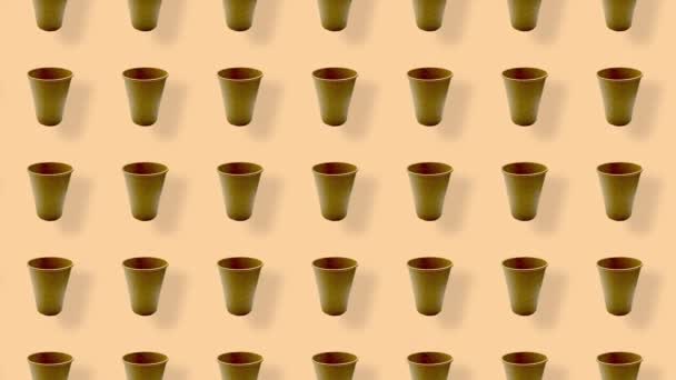 Buntes Muster von Pappbechern auf orangefarbenem Hintergrund mit Schatten. Nahtloses Muster mit Pappbecher. Ansicht von oben. Realistische Animation. 4K-Videobewegung — Stockvideo